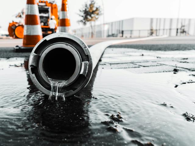 a water pipe with water trickling out into a puddle