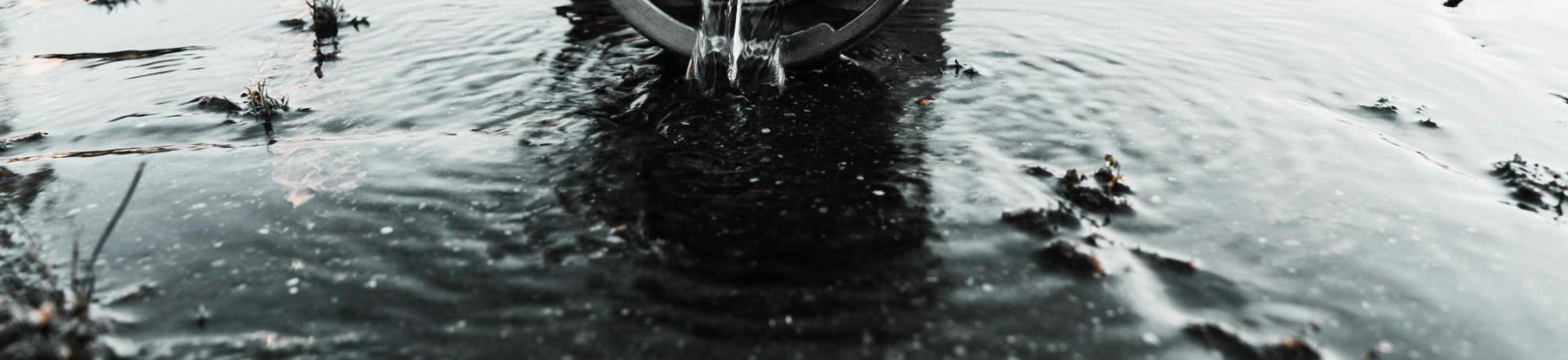 a water pipe with water trickling out into a puddle
